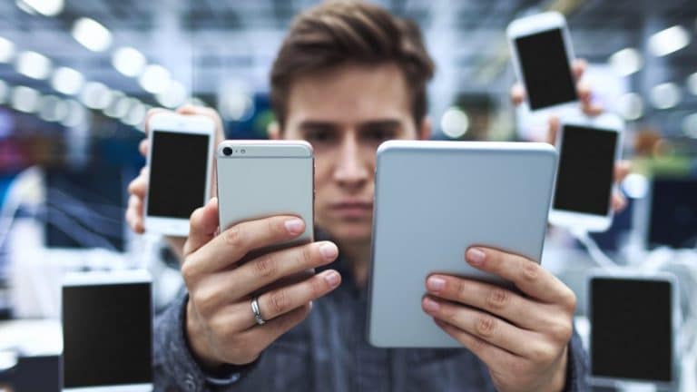 Homme comparant appareils électroniques